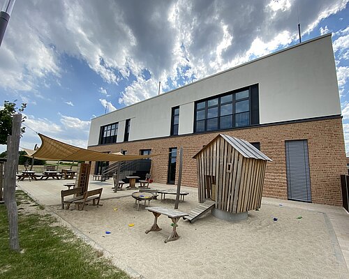 Kitagebäude von der Rückseite mit Sand-Spielplatz