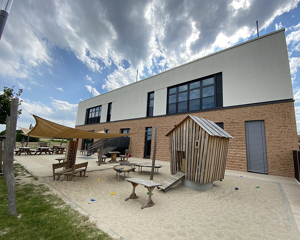Kitagebäude von der Rückseite mit Sand-Spielplatz