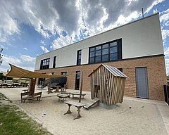 Kita-Gebäude von der Rückseite mit Sand-Spielplatz